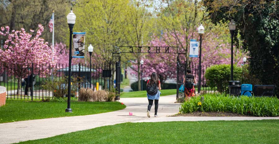 campus scene of student walking through Founder's Gate