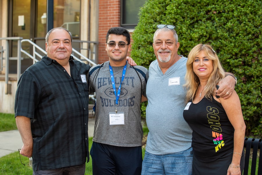 Parents and family posing with a student in front of residence hall