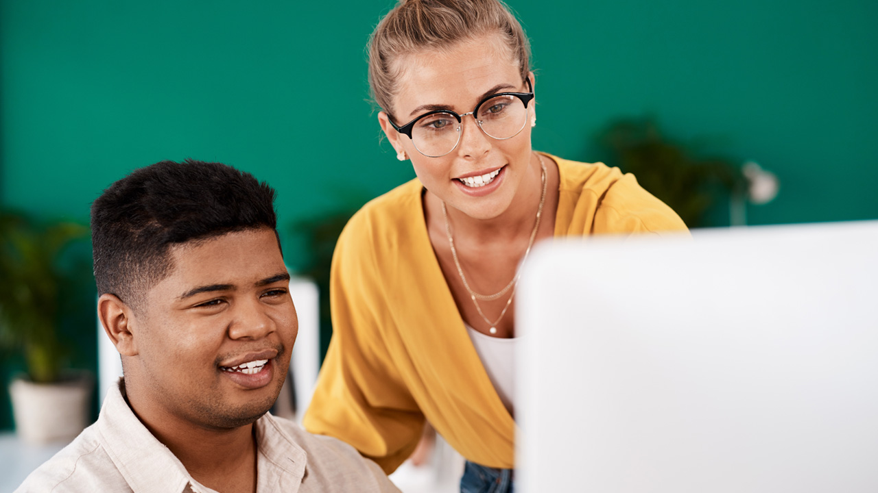 A mentor working with a student on a computer