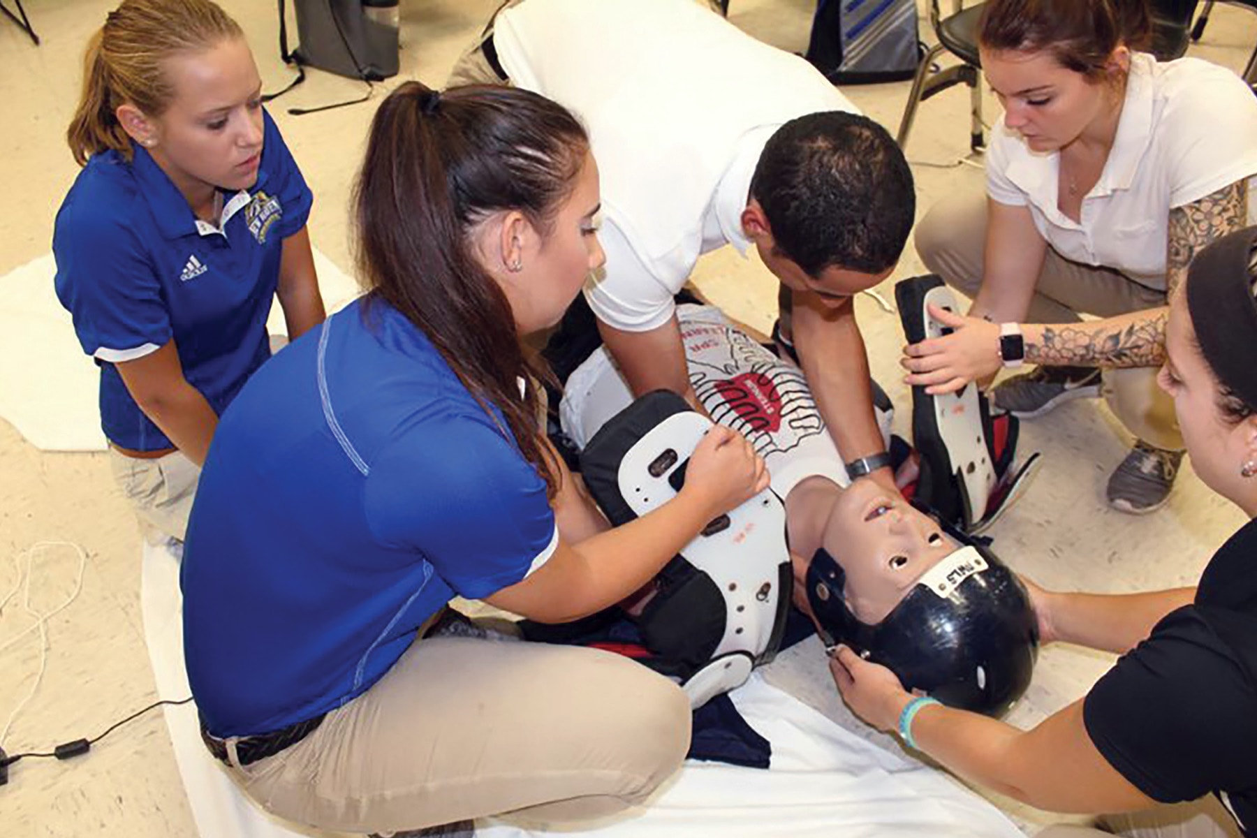 Students observing and checking athlete for injuries