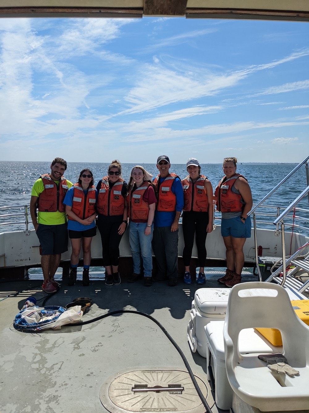 A group of students and faculty on a boat out in the water