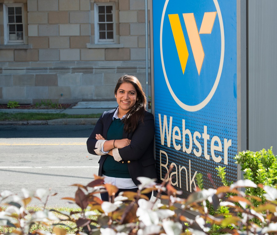 Woman posing in front of a bank with cross arms