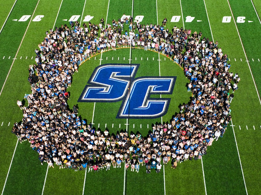 Class in front of the football field with the athletics logo