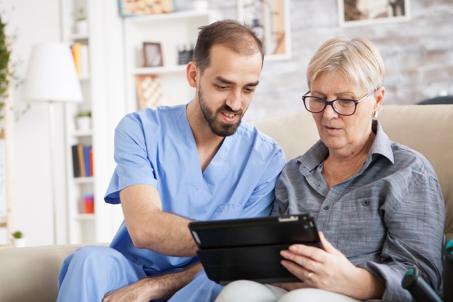 Healthcare worker helping senior woman use tablet