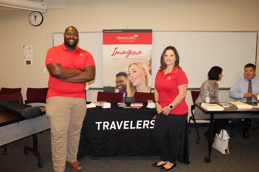 A man to the right and a woman to a left showcasing their program with in a career fair table