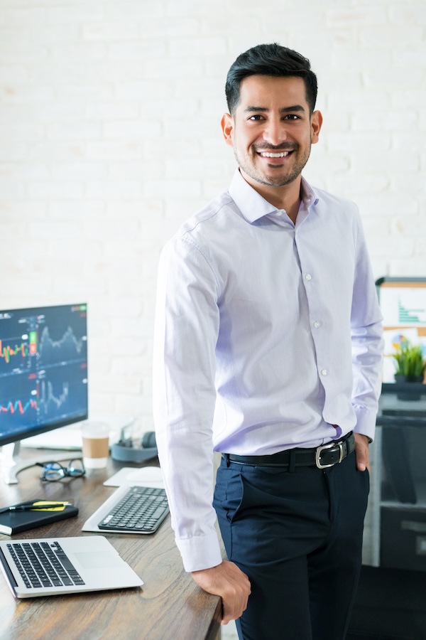 Man posing in front of his desk showing stock graphics