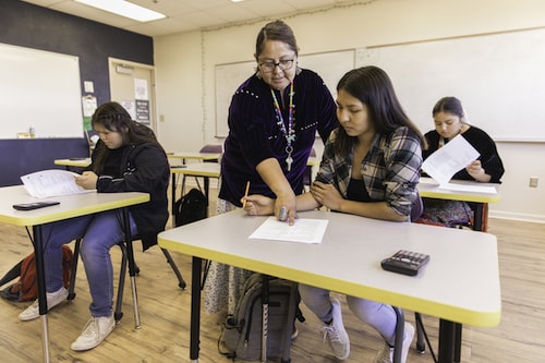 A teacher working with an elementary school student in a classroom
