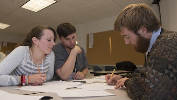2 students and professor reviewing papers