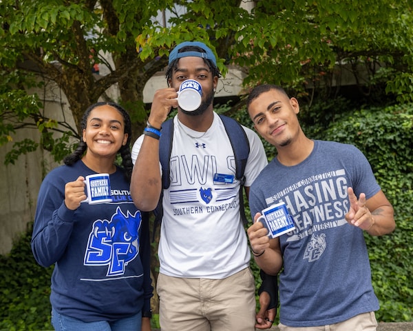 A group of three students wearing SCSU gear and merchandise
