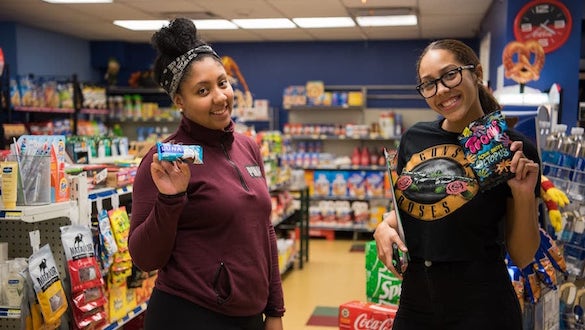 Two students holding snacks at a convenience store