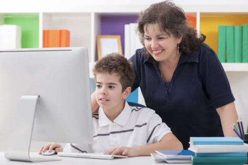 A teacher helping out a student on a computer