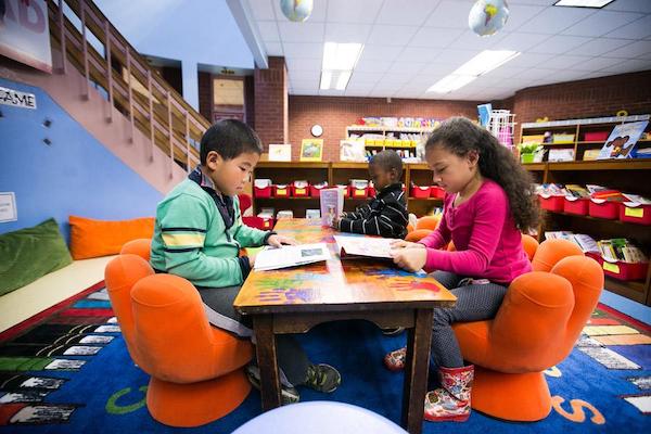 Three children reading in a classroom