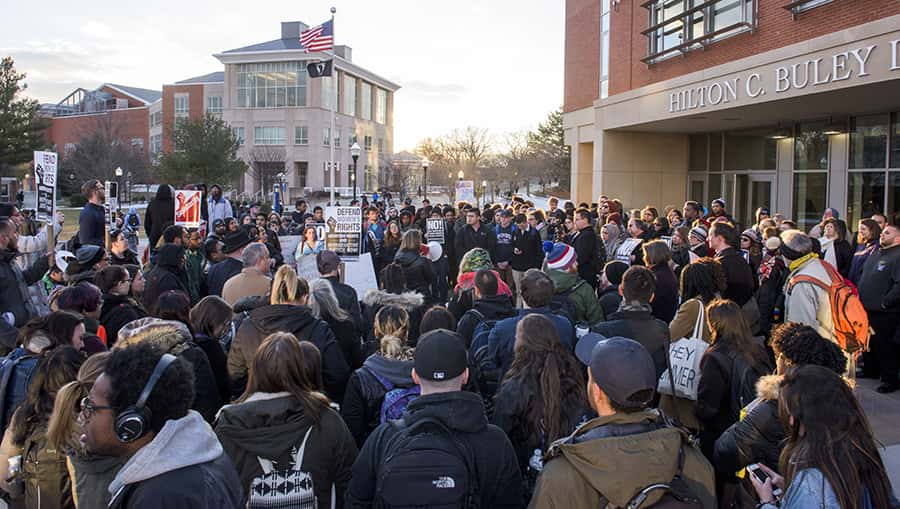 a large group of students, faculty, and staff gather in front of Buley Library for a political rally