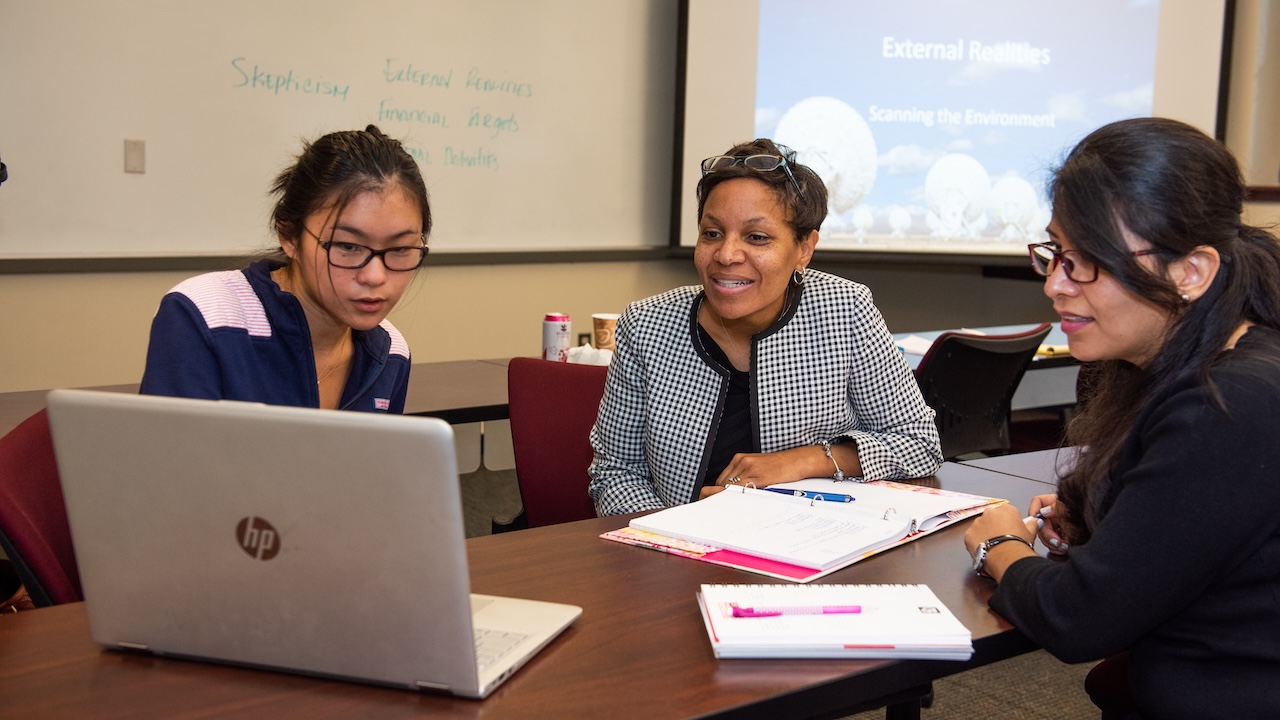 Three students reviewing informaton on a computer