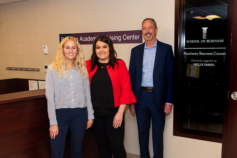 Three Business School faculty members standing in front of the Business Success Center