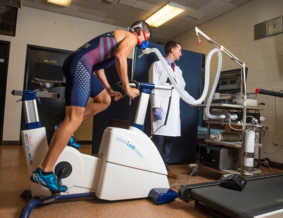 Athlete on a treadmill hooked up to a machine, and a scientist observing the data
