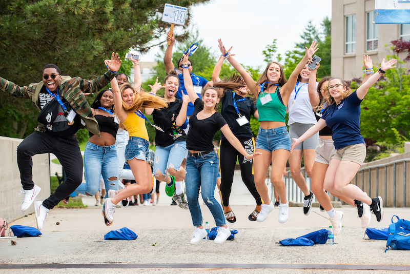 A group of students jumping and posing outside of the student center
