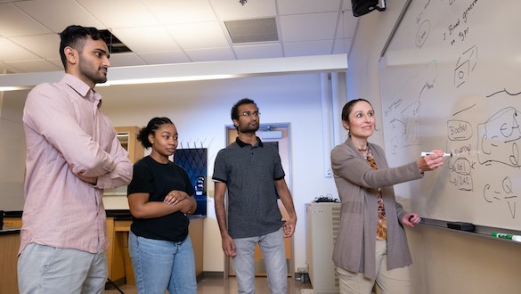 Dr. Christine Broadbridge draws on a whiteboard for students