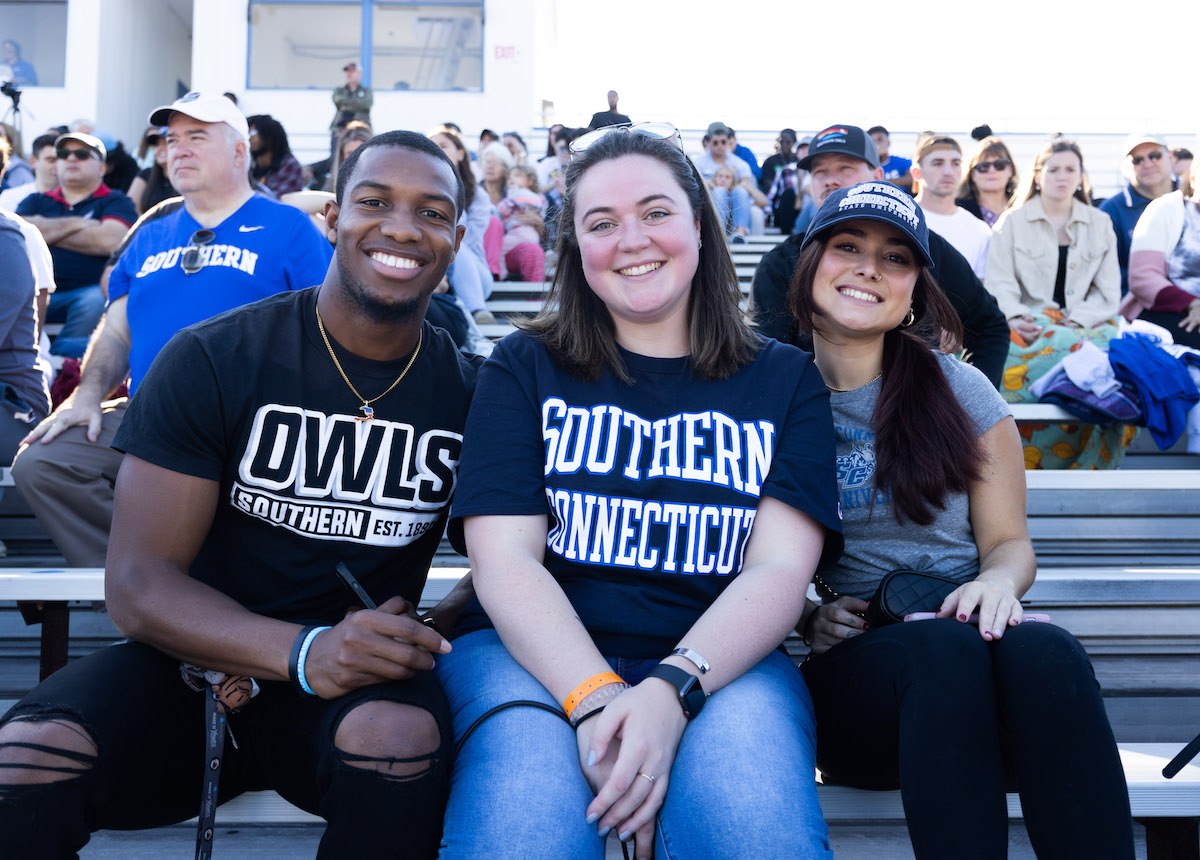 Three people sitting at a football game