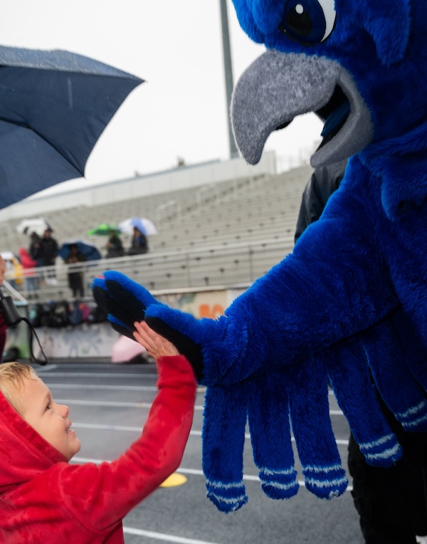 Child hi-fiving Otus the owl mascot