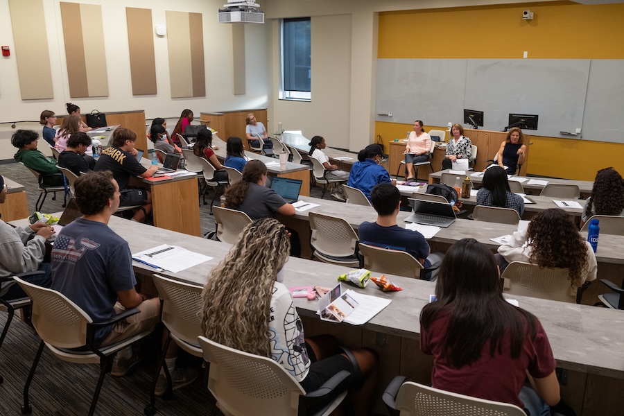 Three business women leaders discussing finance to a class of students