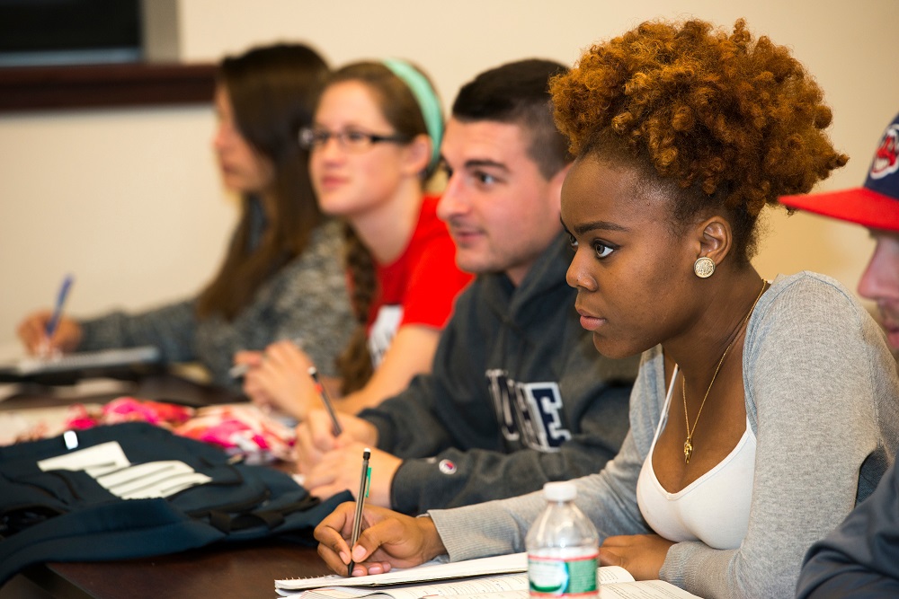 A row of students in a classroom learning and taking notes