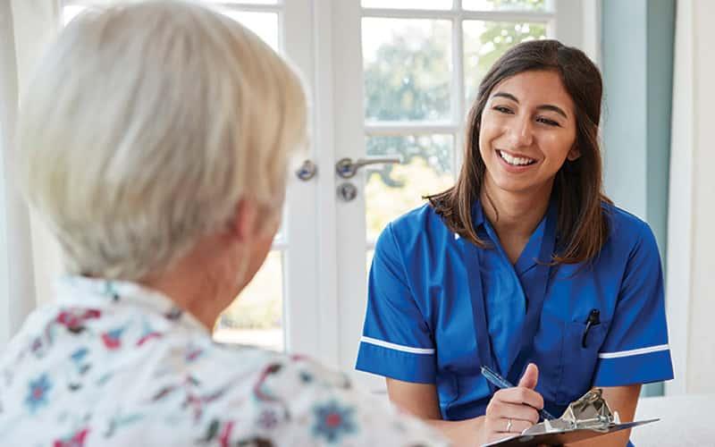 a young woman in scrubs speaks with an elderly patient