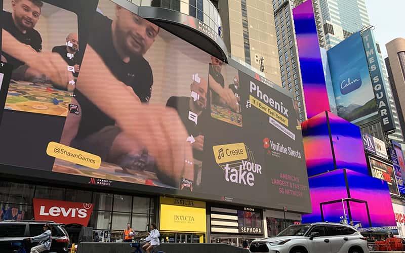 A street scene in New York City, with Shawn Gilhuly's image on an electronic billboard