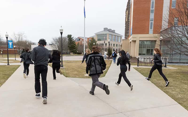 A group of students run across the SCSU campus