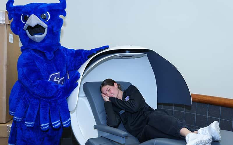 Otus the owl shows off a student pretending to sleep inside a "nap pod"