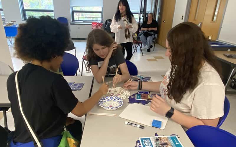 Three students sit together at a table working on a project