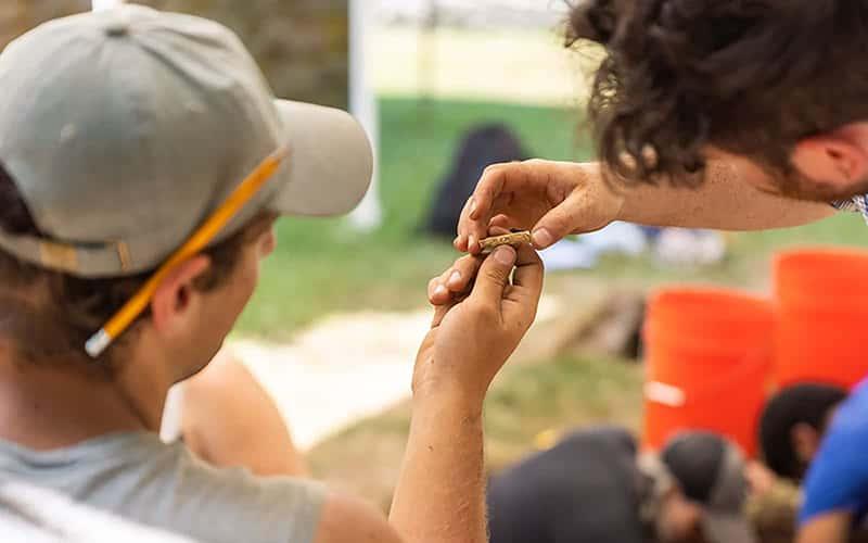 two students closely examine an archaeological find