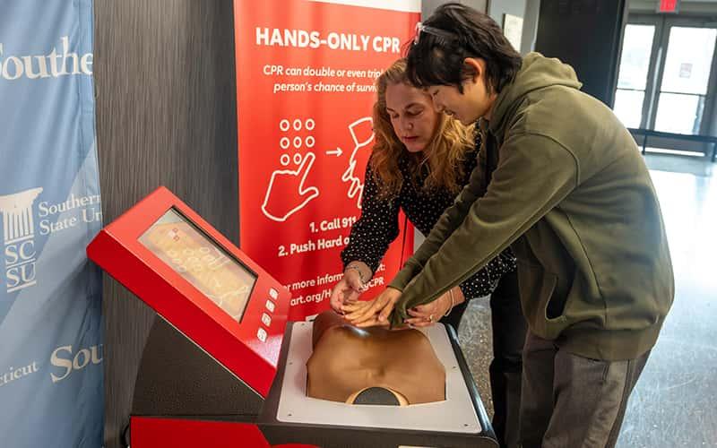 two people practice CPR on a model
