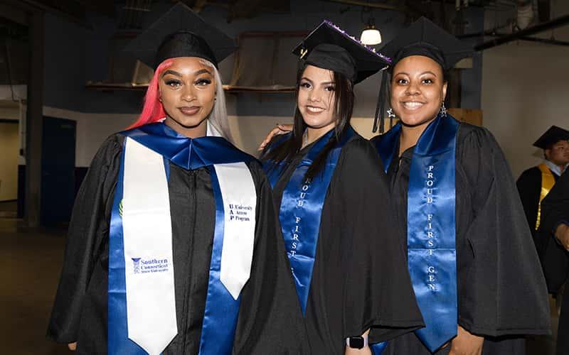 three graduating first-gen students at Southern proudly wear their first-gen stoles at commencement.