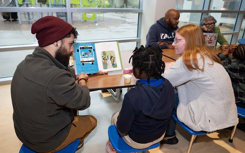 two Southern students read a book to a child at Barack Obama University Magnet School