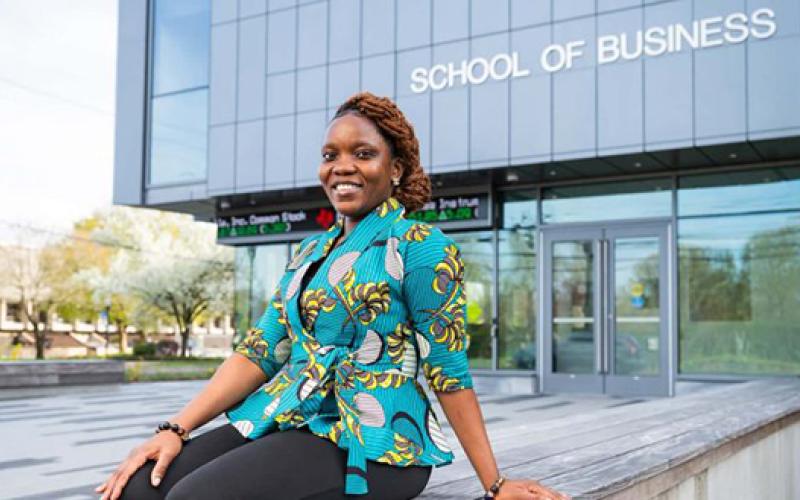 Veronica Opuni sitting outside with the School of Business Building in the background
