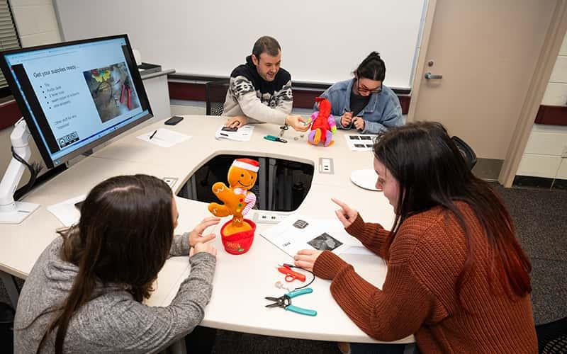 students around a table work on adapting toys for children with disabilities
