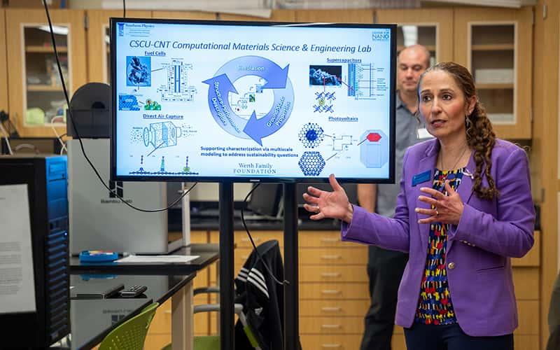 Christine Broadbridge stands next to a large computer monitor