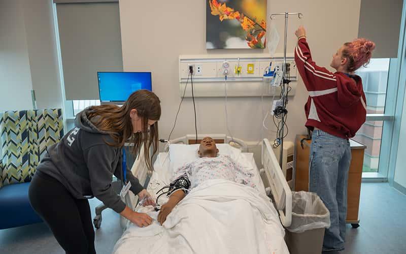 High school students practice nursing skills in a simulated hospital room