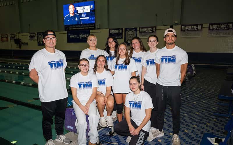 Members of Southern Connecticut State University’s swimming and diving team gather at the Bruce Hutchinson Natatorium following the dedication of the Timothy P. Quill IV Scoreboard on Oct. 9, 2026. Student-athletes wore “Swim for Tim” shirts in honor of the longtime Southern coach.