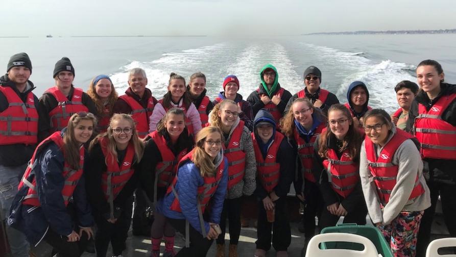 A group of students and faculty out on a ship in the ocean