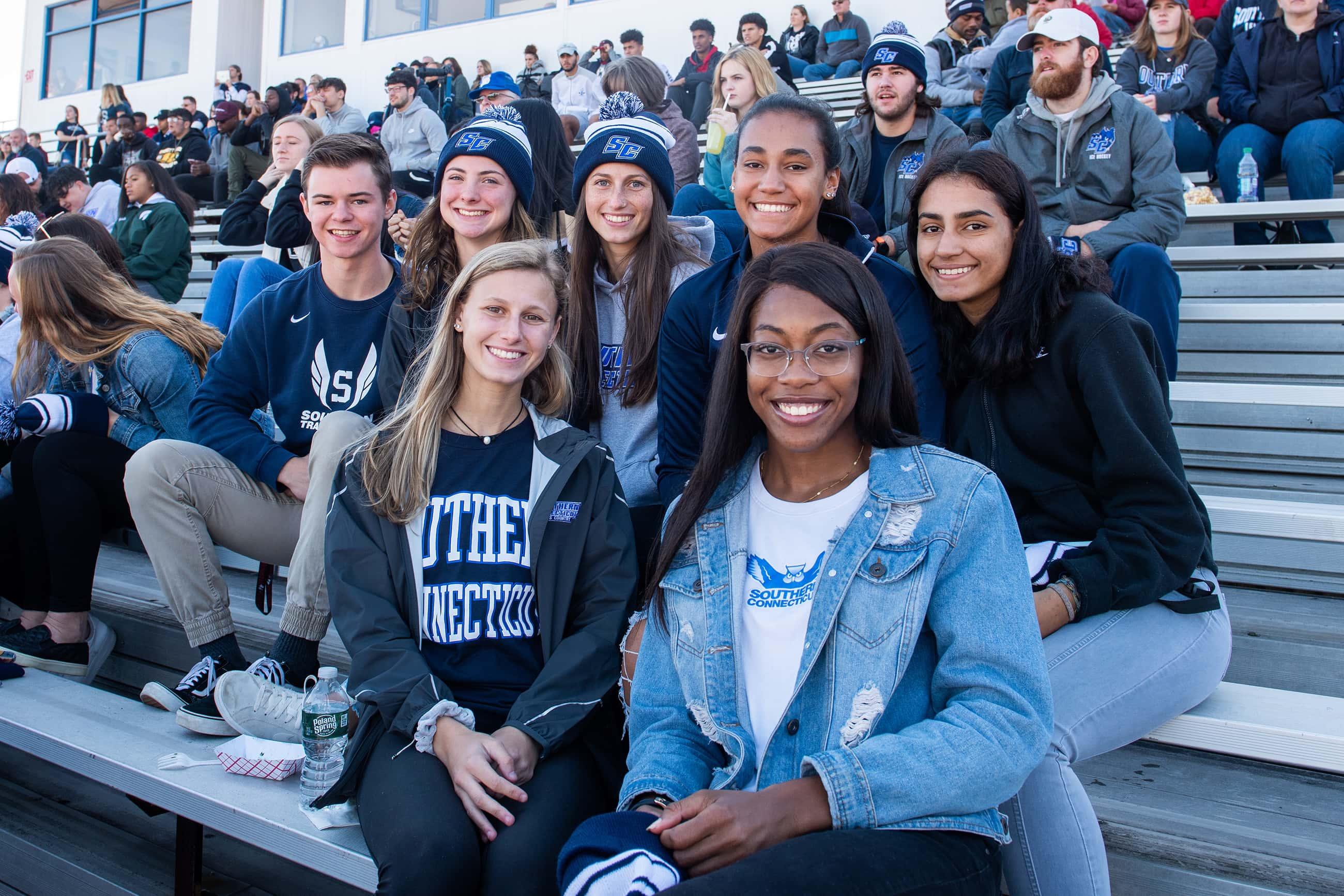 a group of students sit in the bleachers at a football game