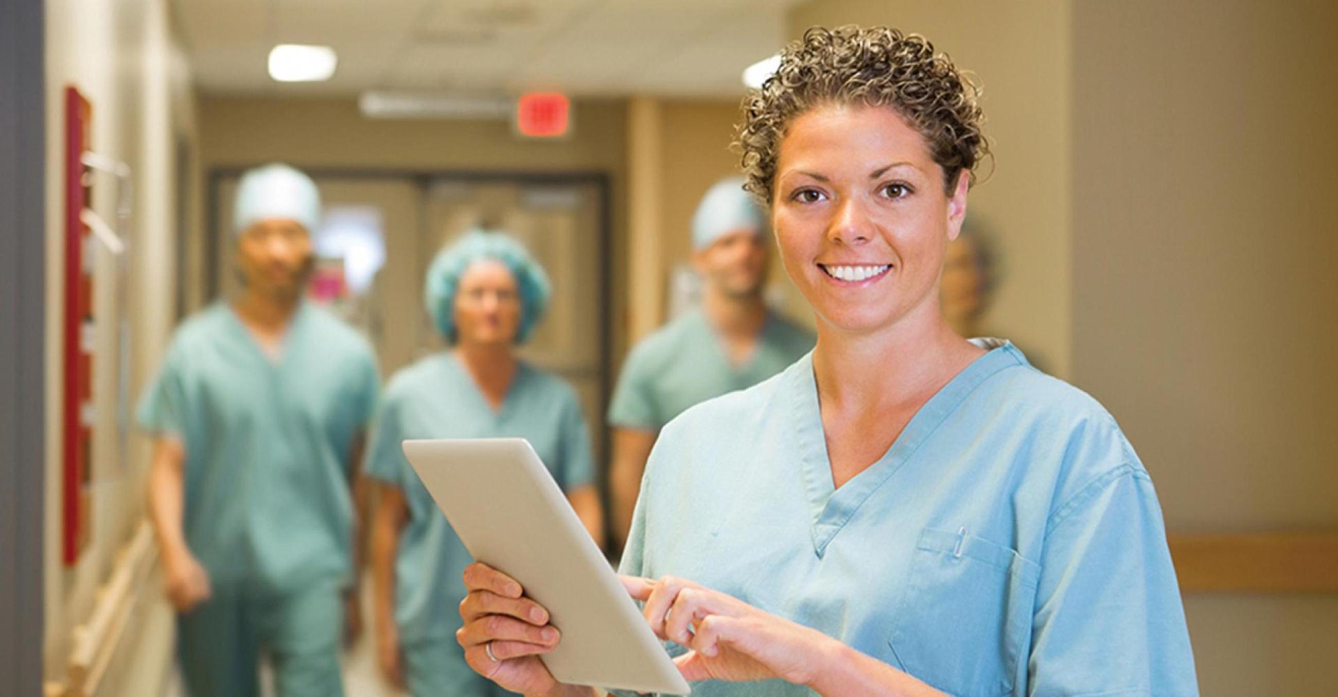 "A healthcare professional in a hospital setting with other medical professionals in the background, blurred"