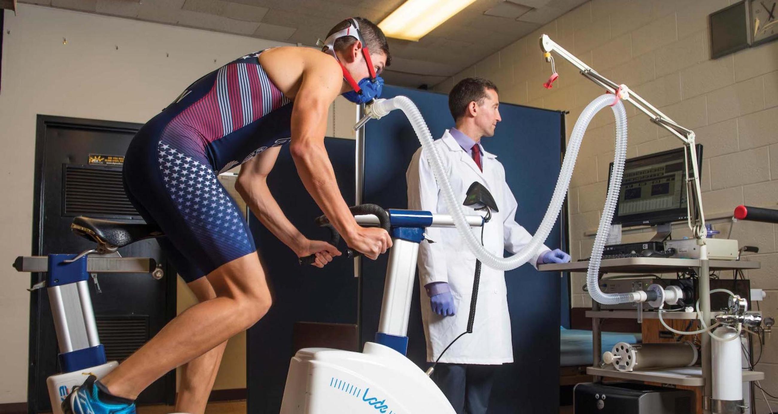 Person on a bike while a professor checks his performance