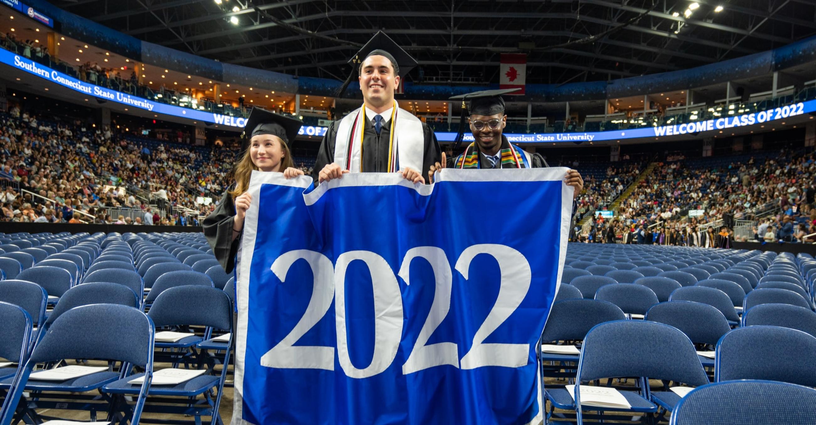 Three graduates holding 2022 sign during commencement