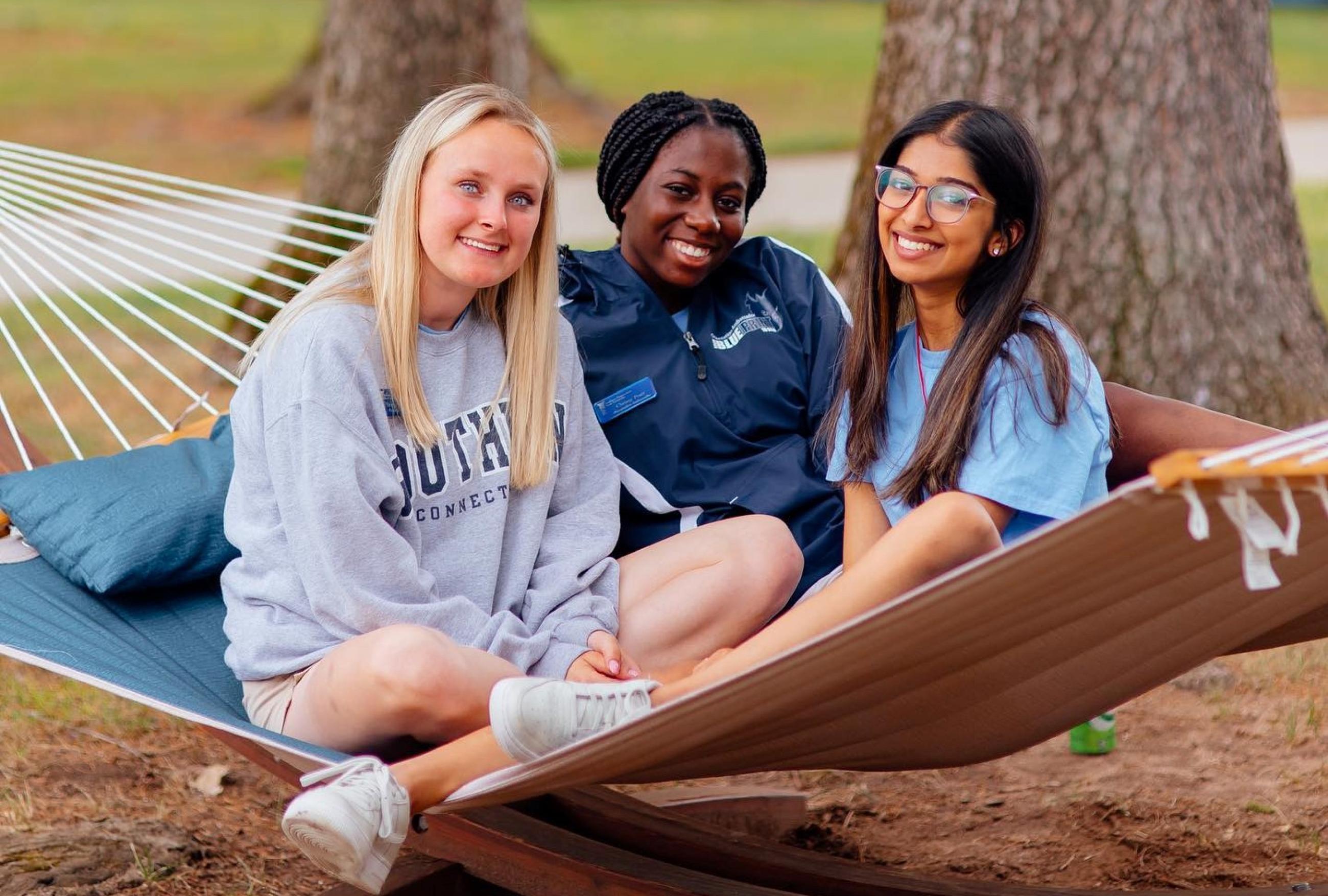 "Three students relaxing outside the residential quad"