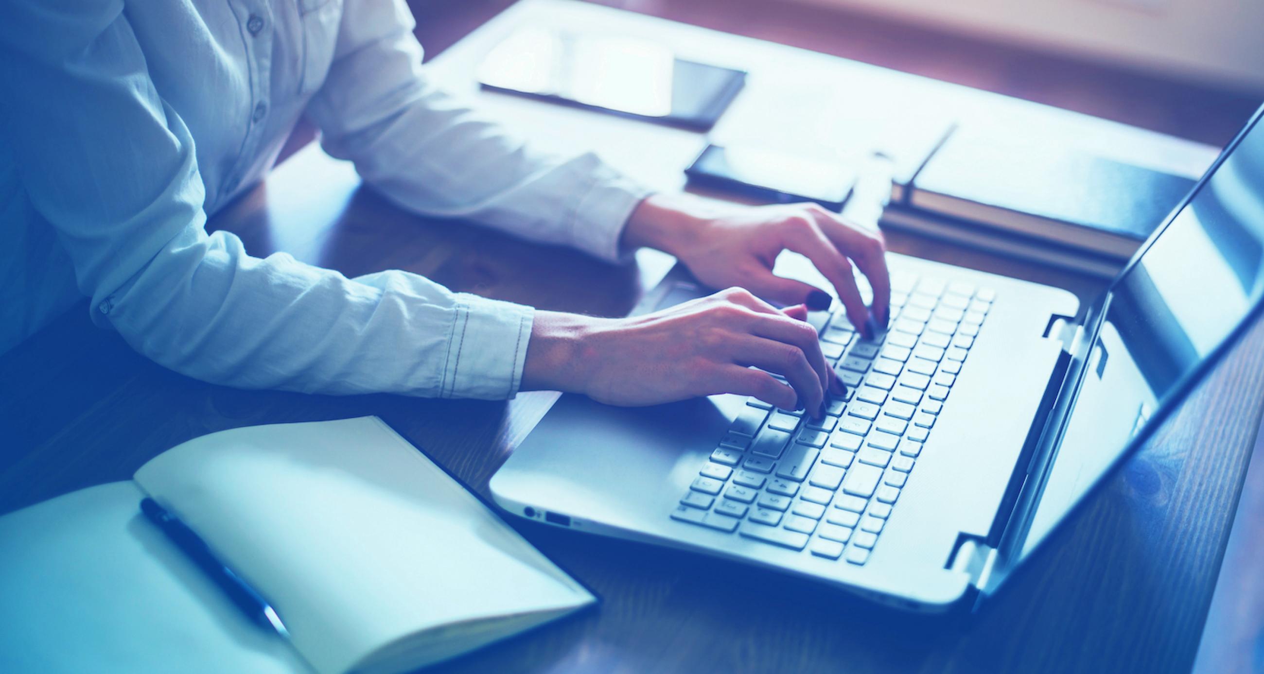 Close-up of a laptop and a person typing