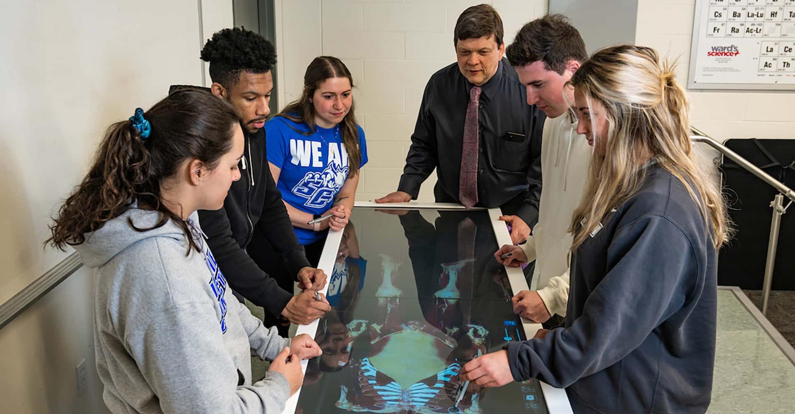 Gary Morin, professor and chairman of the Department of Health and Movement Sciences and students examine a virtual cadaver.