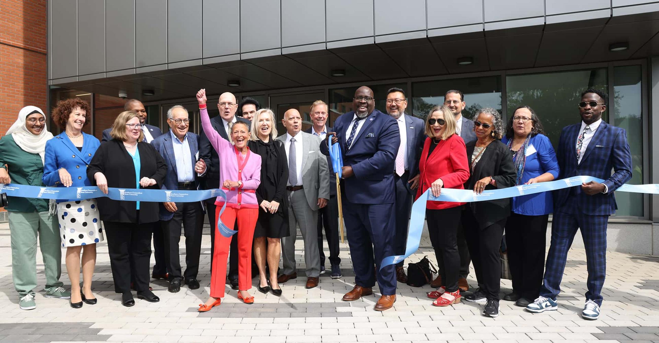 Interim President Dwayne Smith, center, cuts the ribbon on the new School of Business, with the assistance of CSCU Chancellor Terrence Cheng, Governor Ned Lamont, School of Business Dean Jess Boronico, and distinguished guests