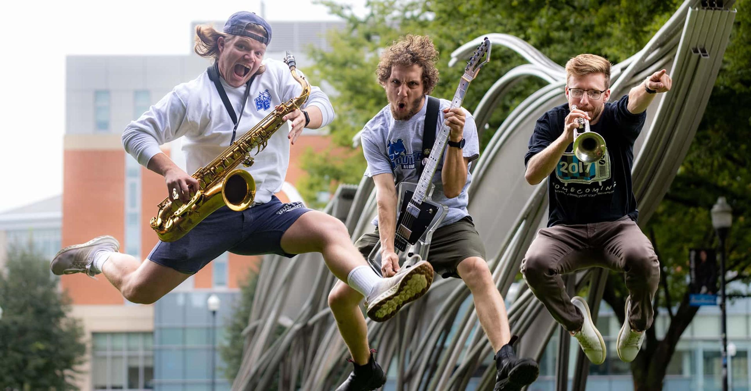 Keegan Smith, ‘22; William Durant, ’19; and Tom Pelton, ’20, members of the band Julai and the Seratones, jump in the air while holding their instruments